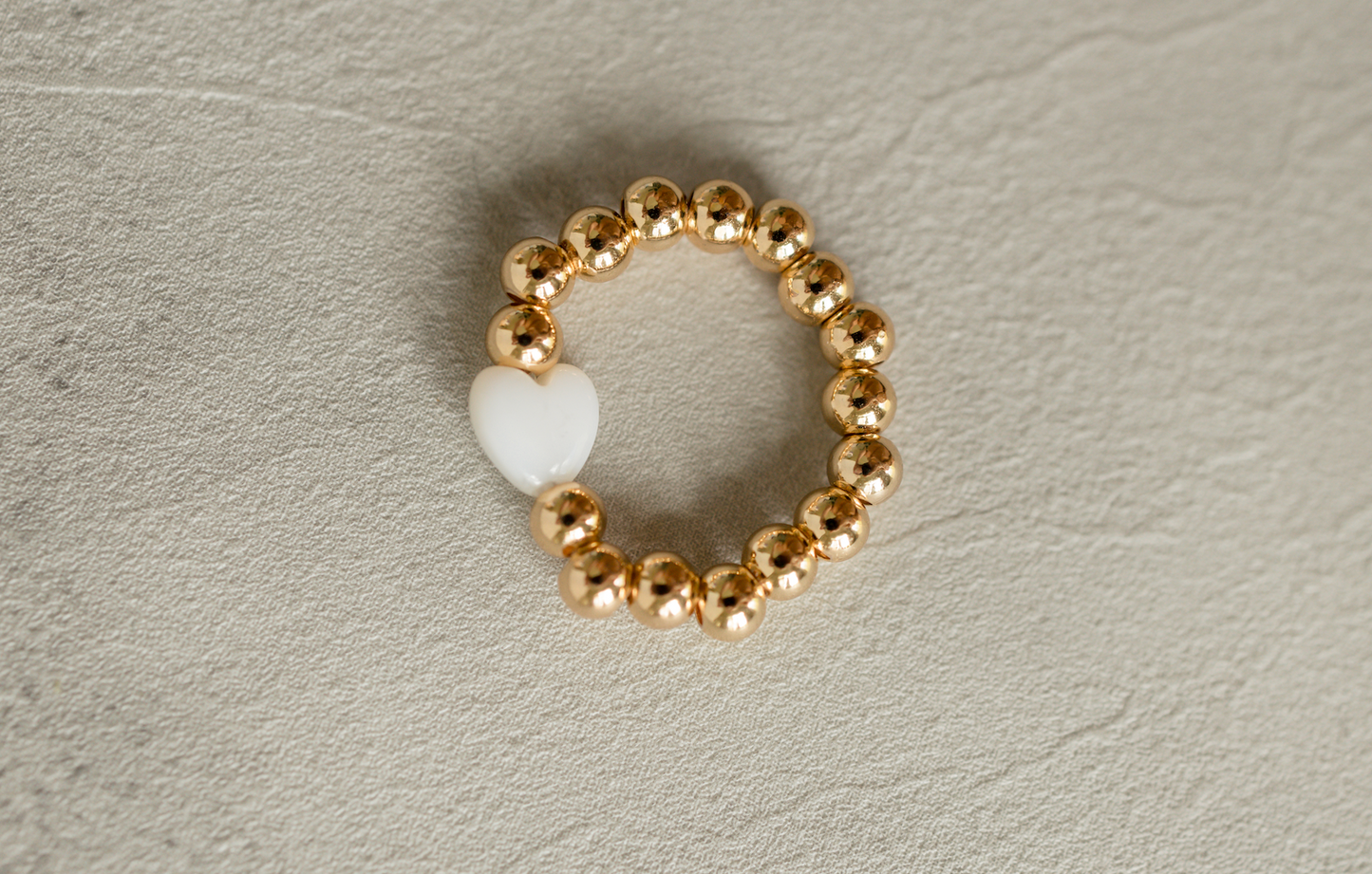 Heart of Gold Ring featuring a white heart bead and gold overlaid brass beads
